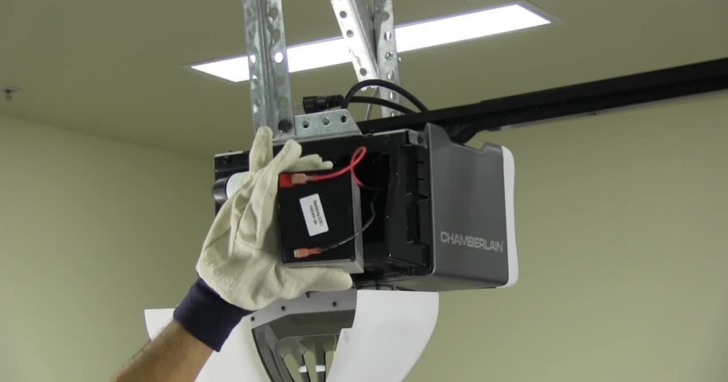 Gloved hand replaces Chamberlain opener battery.